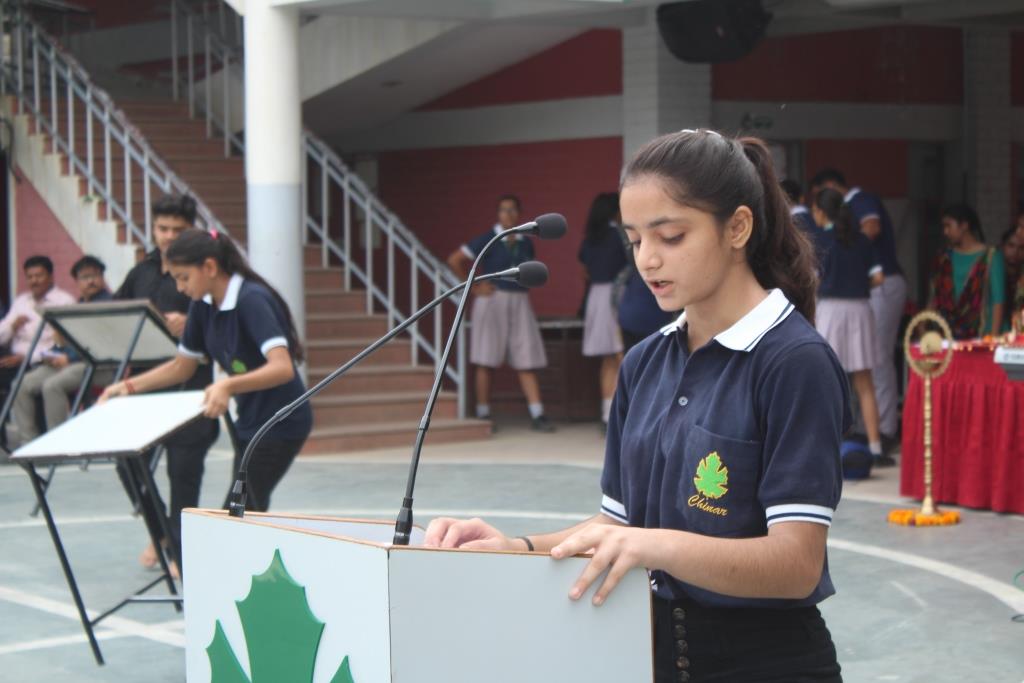 A Chinar student speaking at a school assembly