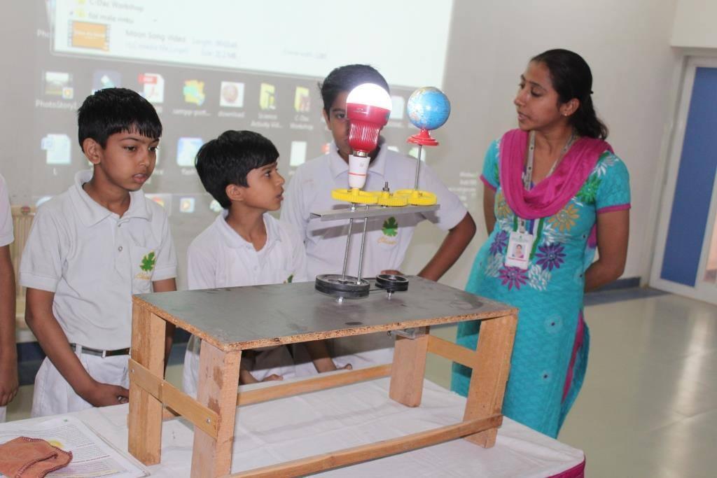 A Chinar teacher guiding students through an interactive classroom model
